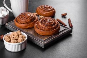 Freshly baked cinnamon roll with spices and cocoa filling on a black background photo