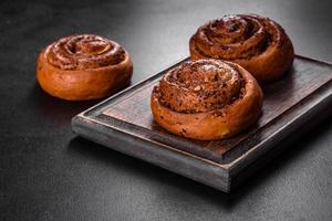 Freshly baked cinnamon roll with spices and cocoa filling on a black background photo