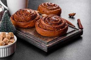 Freshly baked cinnamon roll with spices and cocoa filling on a black background photo