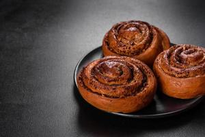 Freshly baked cinnamon roll with spices and cocoa filling on a black background photo