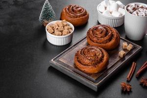 Freshly baked cinnamon roll with spices and cocoa filling on a black background photo