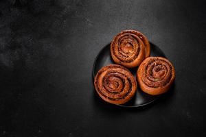 Freshly baked cinnamon roll with spices and cocoa filling on a black background photo