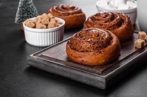 Freshly baked cinnamon roll with spices and cocoa filling on a black background photo