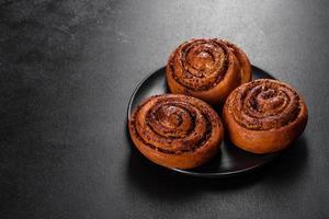 Freshly baked cinnamon roll with spices and cocoa filling on a black background photo