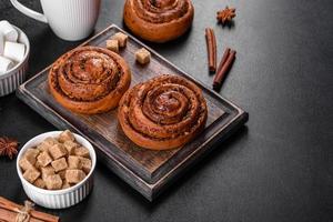 Freshly baked cinnamon roll with spices and cocoa filling on a black background photo