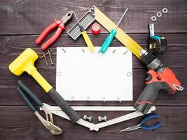 The tool building on the wooden background around the white sheet of paper photo