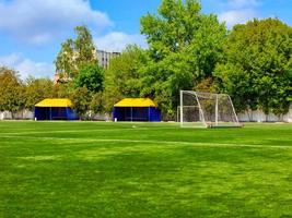 Green lawn of a soccer field with gates and tents for teams players.