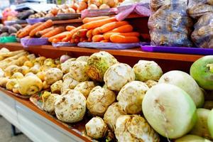 apio, nabo, zanahorias, cebollas, raíces y otras verduras se venden en los estantes del mercado. foto