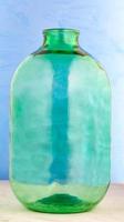 A 10 liter glass jar is made of thick green glass on a blue background. photo