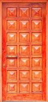 Old orange wooden entrance doors with a bronze handle and symmetrical square panels in Greek style. photo