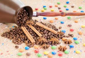 clay jar filled with coffee beans, anise and cinnamon sticks with colorful candies photo