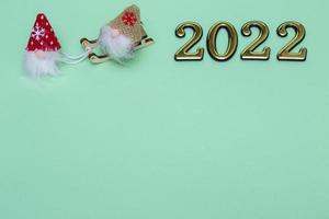 Christmas gnomes on sleigh with golden numbers 2022 on blue background with place for text photo