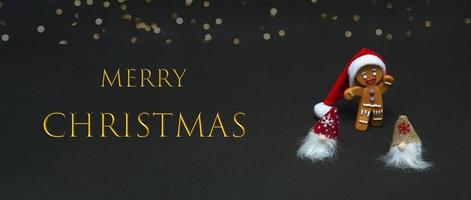 Christmas concept. Gnomes and gingerbread man in santa hat on black background with text photo