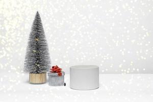 Feliz año nuevo y feliz navidad, un hermoso podio decorado con un árbol de navidad y un regalo de cerca sobre un fondo blanco.