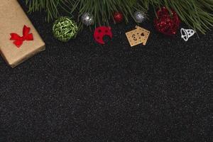 vista superior plana de la maqueta de año nuevo sobre fondo negro brillante con elementos de año nuevo y rama de pino. copia espacio foto