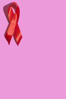 día internacional del sida. cinta roja con una dura sombra sobre un fondo rosa. concepto de concienciación sobre el sida. vertical