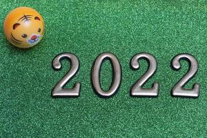 Concepto de año nuevo números dorados 2022 con cara de tigre sobre fondo verde brillante con espacio de copia