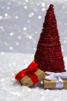 Christmas tree with gifts on the snow against a background of bright bokeh lights. Minimal concept of postcard, invitation card. Close up with copy space photo