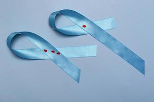 Close up top view of concept for World Diabetes Day 14 November. Blue ribbon with drops of blood on a blue background photo