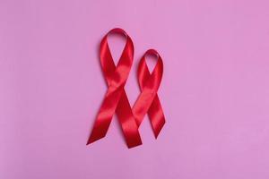 Vista superior sobre fondo rosa con concepto de cinta roja Primer plano del día internacional del sida el 1 de diciembre. foto