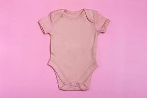 Pink blank baby bodysuit template, mock up close-up on pink background. Baby bodysuit, jumpsuit for newborns. View from above photo