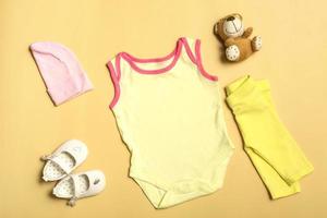 Mockup for design and placement of logos, advertising. Beige baby bodysuit, top view, mock up on a yellow background. photo