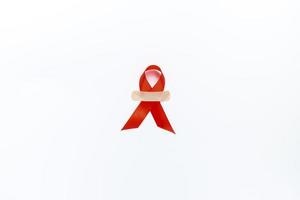 Red AIDS awareness ribbon on white background. Close up copy space. photo