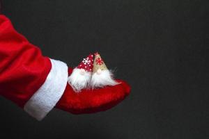 Christmas gnomes in the hand of santa claus on a black background close-up. Festive concept photo