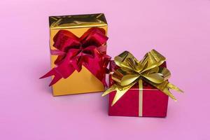 Hermosas cajas de regalo doradas con un lazo rojo sobre un fondo de color vista superior foto