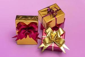 Hermosas cajas de regalo doradas con un lazo rojo sobre un fondo de color, vista superior foto
