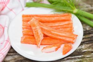 Crab sticks sliced on white plate and vegetable , Fresh crab sticks surimi ready to eat japanese food. photo