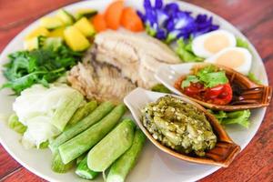 Thailand food Asian cooked tilapia fish - Steamed fish with chili sauce boiled eggs and vegetables pumpkin carrot on white plate photo