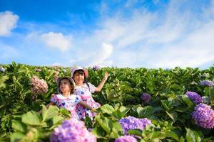 Little asian child girl have fun with a happy smiling face at the morning garden natural flower, Cute girl children kids playing outside on bright day beautiful flower in spring outdoors photo