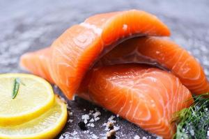 Raw salmon filet with herbs and spices rosemary food lemon on black background photo