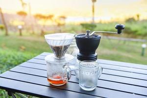 drip coffee barista pouring water on filtered brewing, make cup hand drip coffee in glass jar on outdoors. photo