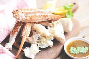 Crab meat - Cooked crab claws and legs on wooden and seafood sauce on the table , blue swimming crab photo