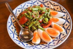 Ensalada picante huevos duros de frijol largo en un plato de comida tailandesa foto