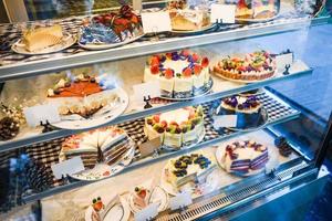 Pastel en la estantería con tarta de muchas variedades en la tienda panadería foto