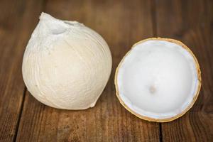 cut half coconut and fresh coconuts on old wooden table for food. photo