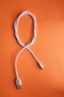 Cable USB enrollado blanco sobre fondo naranja foto