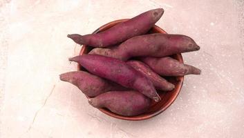 slices of sweet potatoes on wooden background, close up. Raw sweet potatoes or batatas. photo