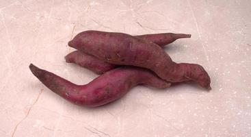 slices of sweet potatoes on wooden background, close up. Raw sweet potatoes or batatas. photo