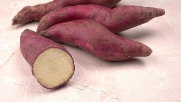 slices of sweet potatoes on wooden background, close up. Raw sweet potatoes or batatas. photo