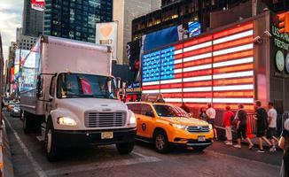 NEW YORK CITY, USA - JUNE 21, 2016. People and traffic in front of famous american led flag of The New York City Police Department in Times Square