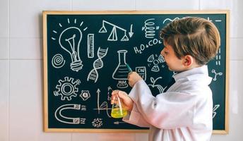 Boy dressed as chemist pointing at blackboard photo