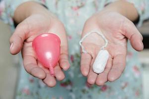 mujer sosteniendo tampón y copa menstrual en sus manos foto