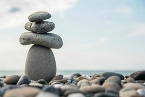Stones pyramid on pebble beach symbolizing stability, zen, harmony, balance. Concept of freedom relaxation photo