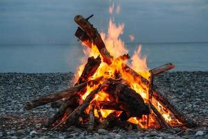 A bonfire on the beach. A bonfire on a stone beach. Fire on the beach - selective focus, copy space. Lonely fire on the seashore photo