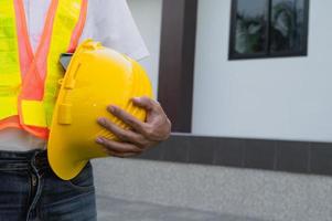 Closeup hand holding hard hat at home construction background photo