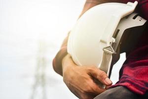 Technician holding white hat safety hard hat sunlight background photo